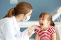 Doctor,checking,little,girl's,throat,in,the,office