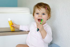 Little,baby,girl,holding,toothbrush,and,brushing,first,teeth.,toddler