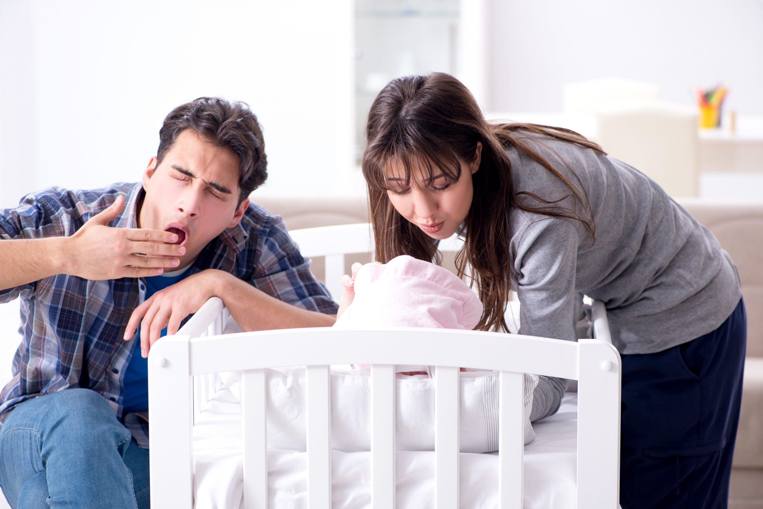Young,parents,with,their,newborn,baby,near,bed,cot