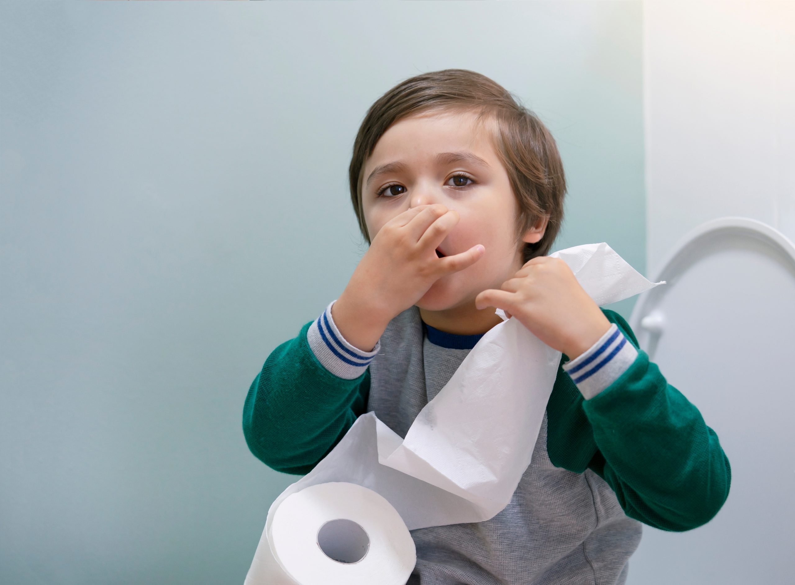 Toddler,boy,sitting,in,the,toilet,and,covers,his,nose