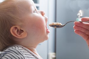 mother,feeds,baby,boy,with,a,spoon,porridge