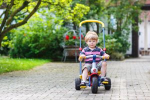 little,toddler,driving,tricycle,or,bicycle,in,home,garden