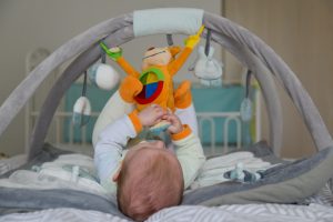 baby,boy,playing,with,hanging,toys,on,developing,mat