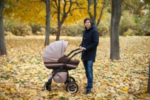 young,man,walking,in,an,autumn,park,with,a,baby