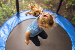 little,girl,jumping,on,a,trampoline,on,a,summer,day.